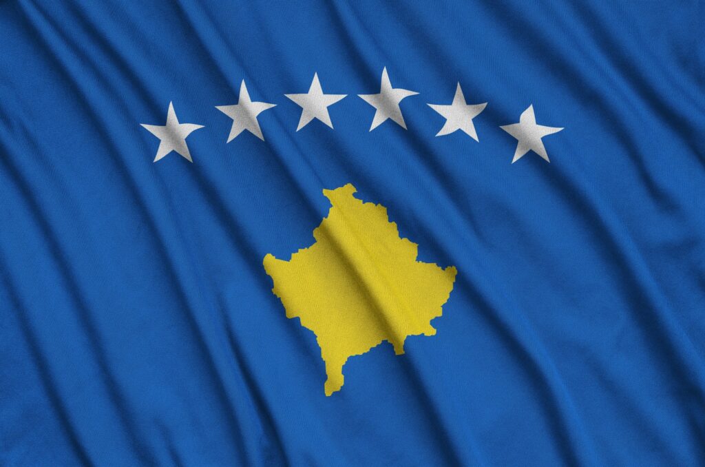 Kosovo flag is depicted on a sports cloth fabric with many folds. Sport team waving banner